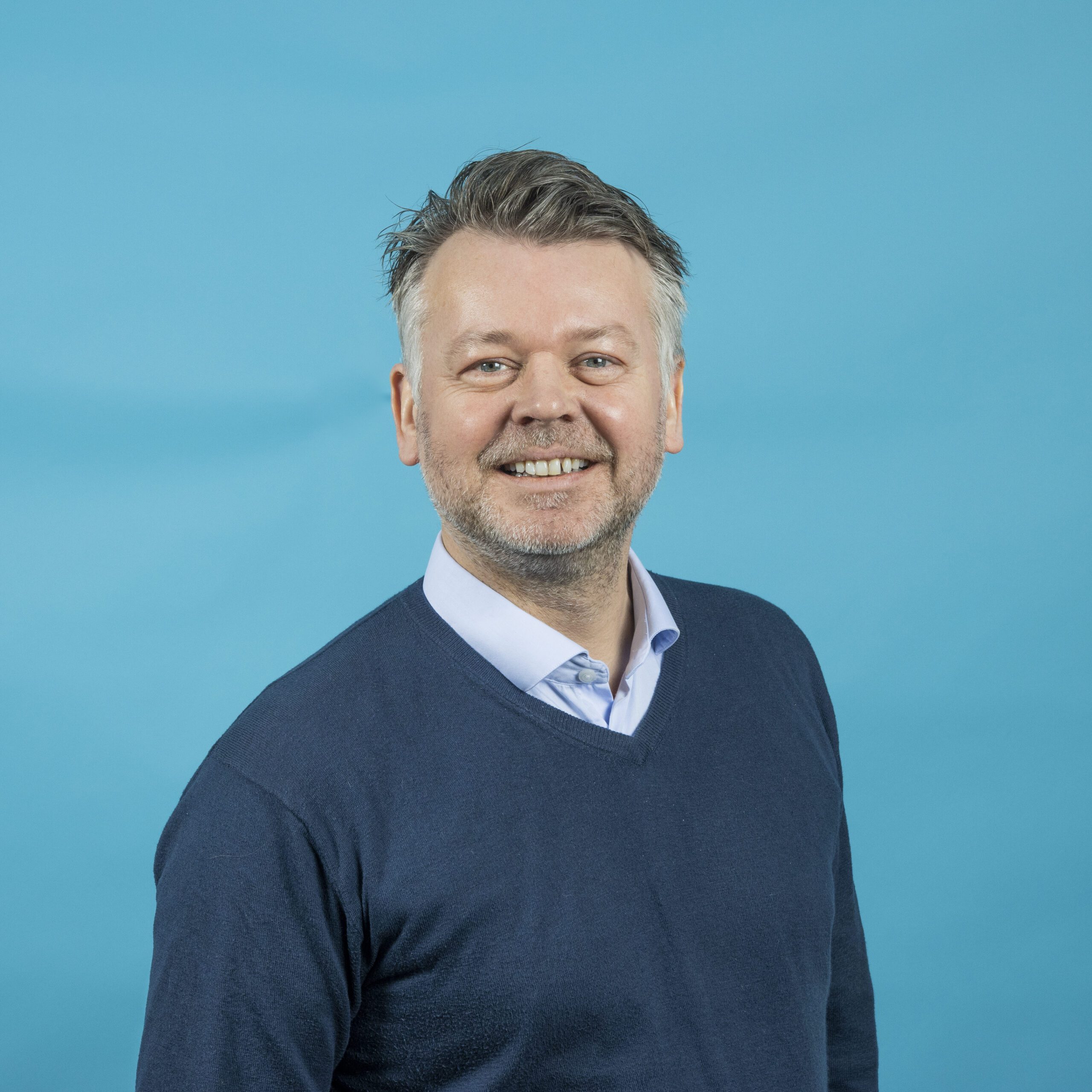 Bilde av Christian Bergh som er daglig leder i Sirius ACT. Portrettbilde med blå bakgrunn - Portrettfoto, Portrettfotografering, Foto & Video, Bedriftsfoto, Bedriftsfotografering, Sarpsborg - Norgency